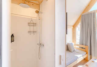 Helles Duschbad und gemütlicher Wohnraum in der Hanna-Lodge im Camping Costa del Sol Glamping Village, Spanien.