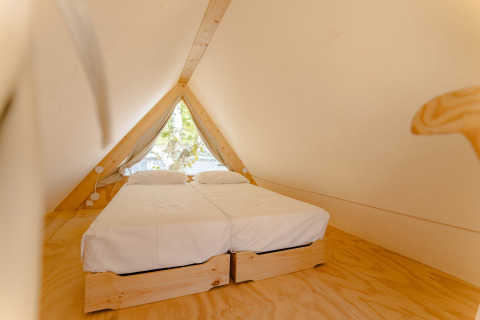 Vista interna di un'accogliente lodge in legno a forma di A con due letti singoli presso Camping Costa del Sol Glamping Village.