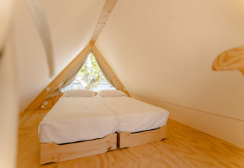 Indvendigt billede af en hyggelig A-formet træhytte med to enkeltsenge i Camping Costa del Sol Glamping Village.