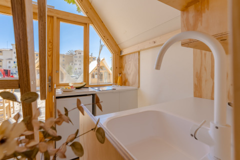 Interno cucina luminosa in una lodge al Camping Costa del Sol Glamping Village, Spagna, vista verso l’esterno.