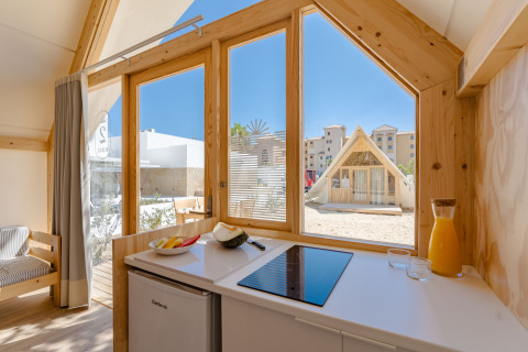 Vista interior de la cabaña Hanna en Camping Costa del Sol Glamping Village, España, mostrando cocina y exterior.