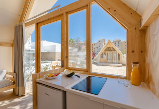 Vista interior de la cabaña Hanna en Camping Costa del Sol Glamping Village, España, mostrando cocina y exterior.