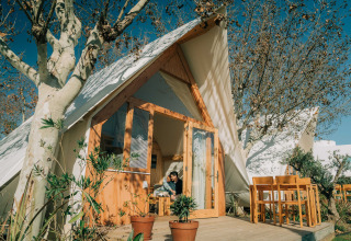 Vista esterna del lodge Hanna al Camping Costa del Sol Glamping Village in Spagna, con tavolo all'aperto e alberi.
