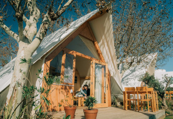 Exterior view of the Hanna lodge at Camping Costa del Sol Glamping Village in Spain, with outdoor seating and trees.