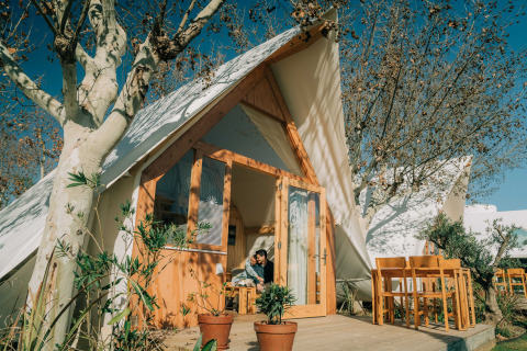 Außenansicht der Hanna-Lodge im Camping Costa del Sol Glamping Village, Spanien, mit Holzterrasse und Bäumen.