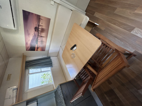 Comedor del Bungalow Essential Banya en TAIGA Delta de l'Ebre, España, con mesa y sillas de madera.