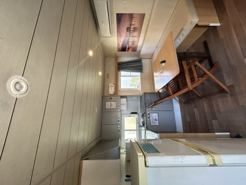 Interior del Bungalow Essential Banya en TAIGA Delta de l'Ebre, España, con mesa de comedor y cocina pequeña.