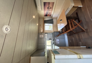 Interior del Bungalow Essential Banya en TAIGA Delta de l'Ebre, España, con mesa de comedor y cocina pequeña.