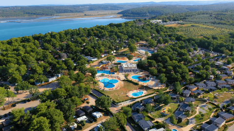 Vista aerea del Camping Lanterna in Istria, Croazia, con piscine, aree verdi e costa vicina.
