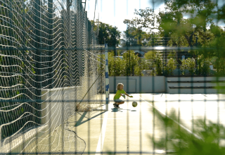 Child playing with a ball on a sunny sports court at Camping Lanterna holiday park in Istria, Croatia.