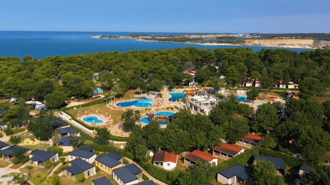 Vista aerea del Camping Lanterna in Istria, Croazia, con piscine, bungalow e la costa visibile sullo sfondo.