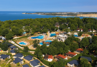 Vista aerea del Camping Lanterna in Istria, Croazia, con piscine, bungalow e la costa visibile sullo sfondo.