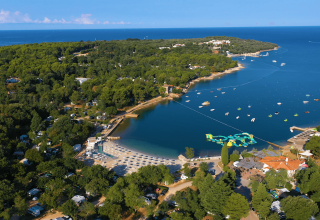 Luftfoto af Camping Lanterna i Istrien, Kroatien med strand, skov og det blå Adriaterhav i baggrunden.