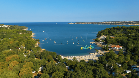Vista aérea del Camping Lanterna en Istria, Croacia, con playa de arena, mar y un entorno verde frondoso.