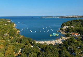 Vista aerea del Camping Lanterna in Istria, Croazia, con spiaggia sabbiosa, mare azzurro e tanto verde.