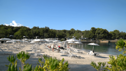 Strand met ligstoelen en parasols op Camping Lanterna, een vakantiepark in Istrië, Kroatië.