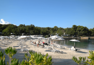 Strand med liggestole og parasoller ved Camping Lanterna, en populær feriepark i Istrien, Kroatien.