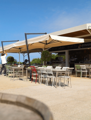 Zona de comedor al aire libre en Camping Lanterna, Istria, Croacia, con mesas, sillas y sombrillas al sol.