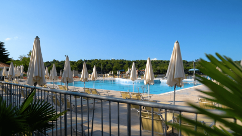 Zona de piscina al aire libre con tumbonas y sombrillas en Camping Lanterna, Istria, Croacia, día soleado.