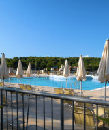 Zona de piscina al aire libre con tumbonas y sombrillas en Camping Lanterna, Istria, Croacia, día soleado.