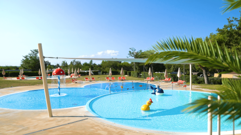 Piscina infantil con juguetes acuáticos y tumbonas en Camping Lanterna, Istria, Croacia, en un día soleado.