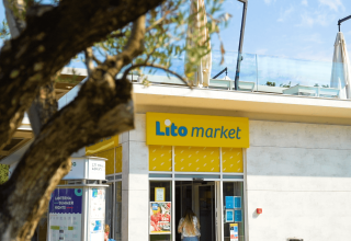 Entree van Lito Market bij Camping Lanterna vakantiepark in Istrië, Kroatië, met een boom op de voorgrond.