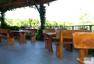 Wooden benches and tables on an outdoor terrace surrounded by greenery at Camping Lanterna, Istria, Croatia.