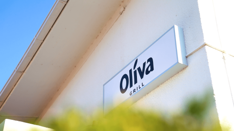 El letrero de Oliva Grill en Camping Lanterna, un parque vacacional en Istria, Croacia, bajo un cielo azul.