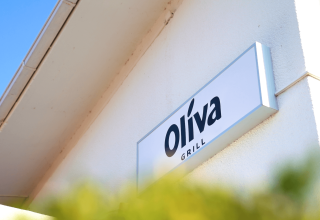 Insegna di Oliva Grill al Camping Lanterna, villaggio turistico in Istria, Croazia, con cielo azzurro.