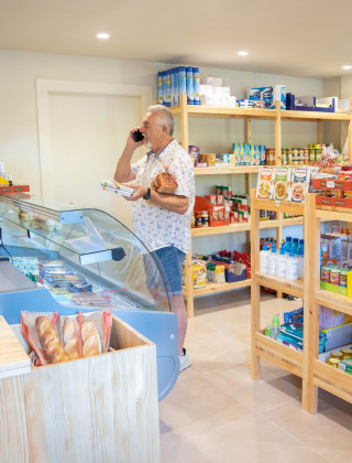 Cliente comprando en el minimercado del parque vacacional TAIGA Lake Caspe en Aragón, España, con productos variados.