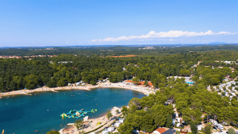Vista aérea de Camping Valkanela en Istria, Croacia, con playa, mar azul y zonas verdes llenas de campistas.