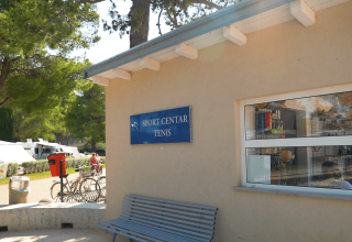 Edificio Sport Center Tenis con panchina fuori, circondato da alberi al Camping Valkanela, Istria, Croazia