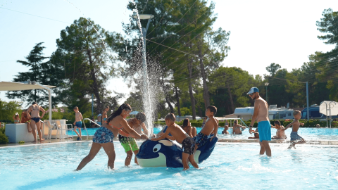 Niños juegan con juguetes inflables en una piscina al aire libre en Camping Valkanela, Istria, Croacia.