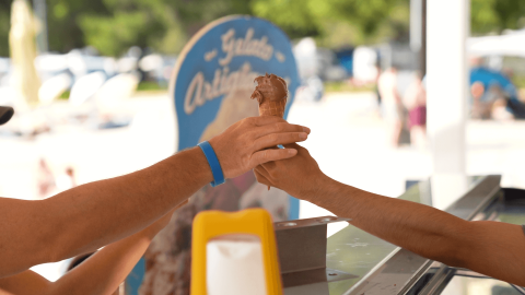 Una persona riceve un gelato al cioccolato in cono presso un chiosco al Camping Valkanela, Istria, Croazia.