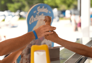 Una persona riceve un gelato al cioccolato in cono presso un chiosco al Camping Valkanela, Istria, Croazia.