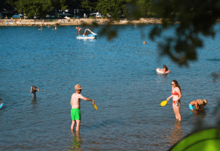 Folk nyder sommersjov i det lave vand ved Camping Valkanela i Istrien, Kroatien, med badestrande og spil.