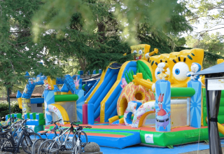 Spongebob-themed inflatable playground with bikes in front, surrounded by trees at Camping Valkanela, Istria.