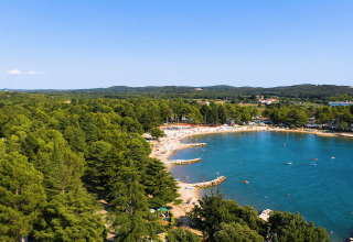 Veduta aerea del Camping Valkanela in Istria, Croazia, con spiaggia, baia blu e alberi verdi circostanti.