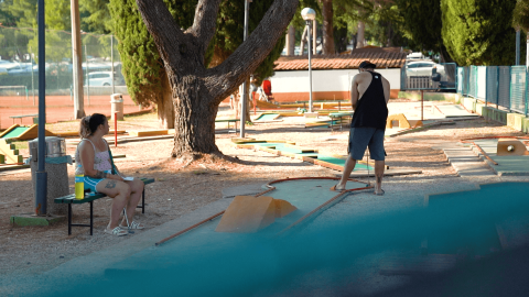 Due persone giocano a minigolf al Camping Valkanela, un villaggio turistico in Istria, Croazia, in una giornata soleggiata.