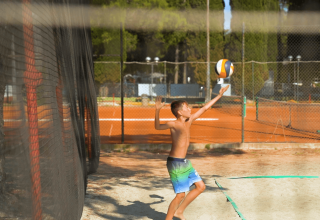 Dreng spiller volleyball på en udendørs bane i Camping Valkanela feriepark, Istrien, Kroatien.