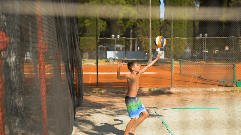 Niño juega al voleibol en una cancha al aire libre en el Camping Valkanela, Istria, Croacia.