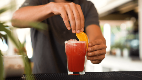 Barkeeper serviert einen roten Cocktail mit Orangenscheibe im Camping Valkanela, Istrien, Kroatien.