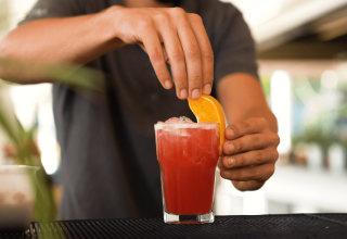 Barman serveert een rode cocktail met sinaasappel bij Camping Valkanela, Istrië, Kroatië.