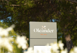 Skilt for Oleander Real Grill-restaurant omgivet af træer på Camping Valkanela, Istrien, Kroatien.