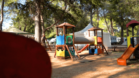 Area giochi colorata tra gli alberi con scivoli, tunnel e tende al Camping Valkanela, Istria, Croazia.