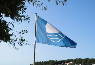 Blue Flag flying at Camping Valkanela in Istria, Croatia, signaling the beach’s high environmental quality.