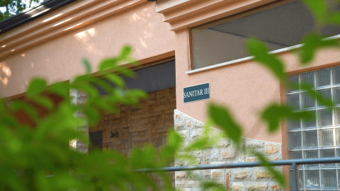 Ingresso dell’edificio SANITAR III al Camping Valkanela, villaggio turistico in Istria, Croazia, nascosto da foglie.