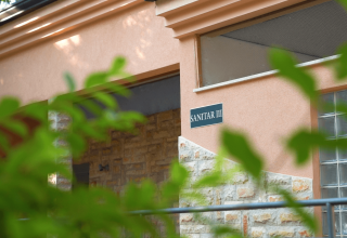 Ingresso dell’edificio SANITAR III al Camping Valkanela, villaggio turistico in Istria, Croazia, nascosto da foglie.