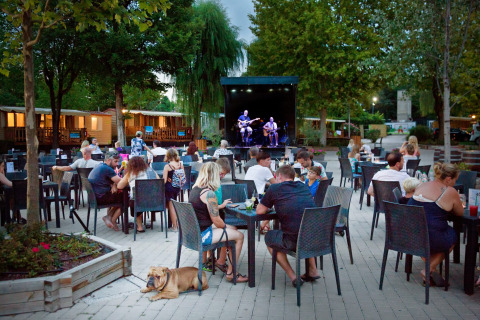 Personas cenando al aire libre y disfrutando de música en vivo en Altomincio Family Park en Lombardía, Italia.
