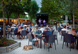 Buiten eten mensen en luisteren naar livemuziek in Altomincio Family Park, Lombardije, Italië.